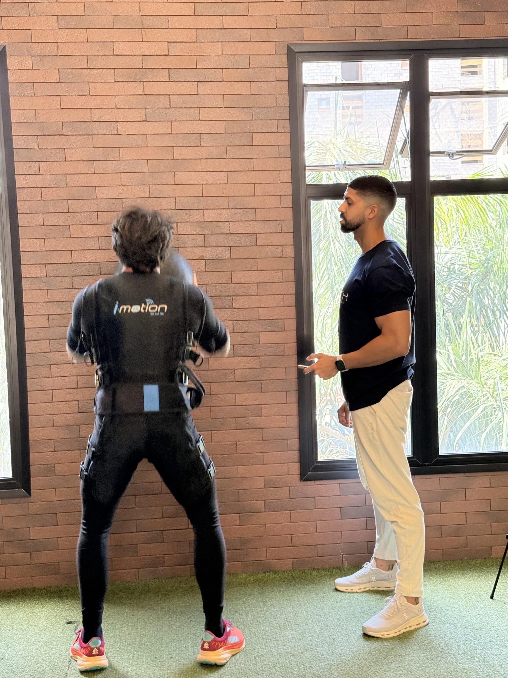 Homem se exercitando com roupa de EMS e com o acompanhamento especializado