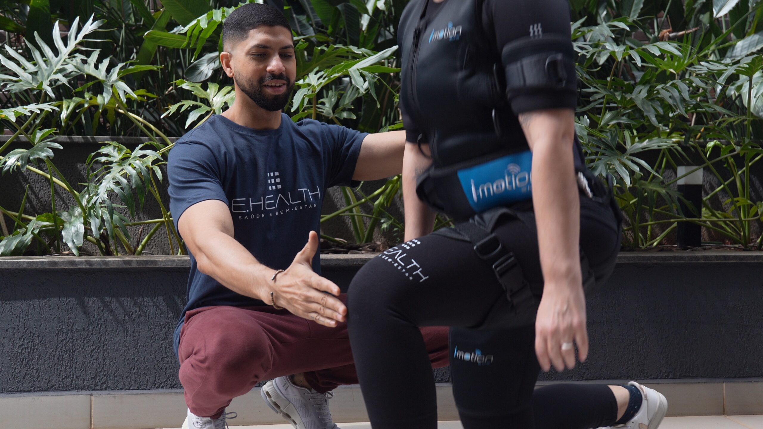 Personal trainer faz sinal de positivo ao lado de cliente em treino ao ar livre