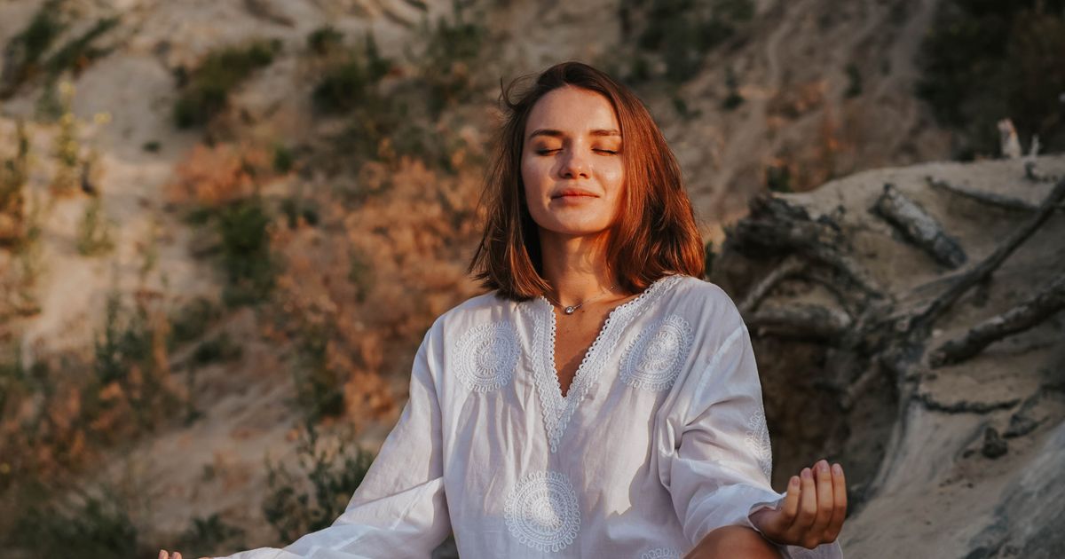 Mulher meditando ao ar livre, representando equilíbrio e bem-estar