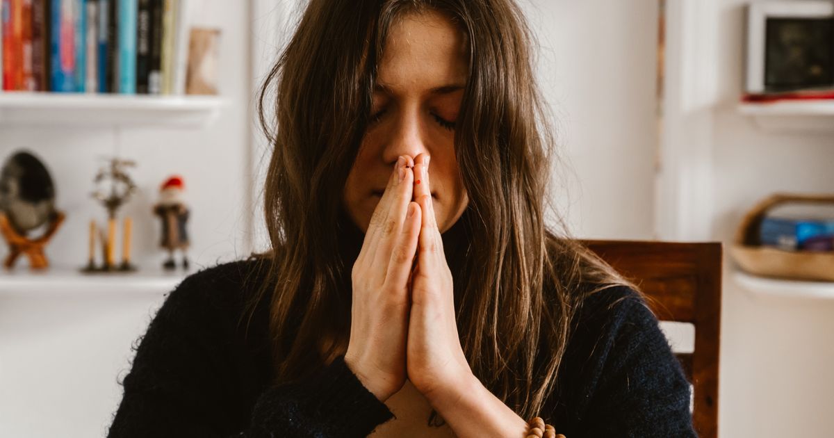 Mulher com as palmas unidas meditando, representando calma e autocuidado