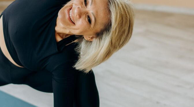 Mulher madura praticando yoga em casa, representando bem-estar e autoestima