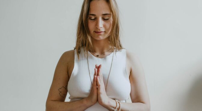 Mulher praticando yoga em um quarto, representando bem-estar