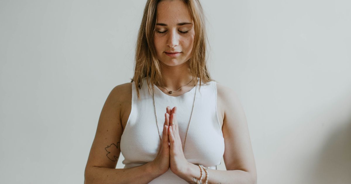 Mulher praticando yoga em um quarto, representando bem-estar