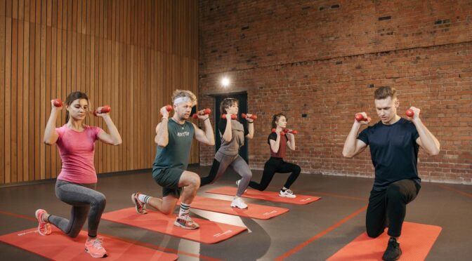 Pessoas se exercitando com halteres, representando estímulo muscular
